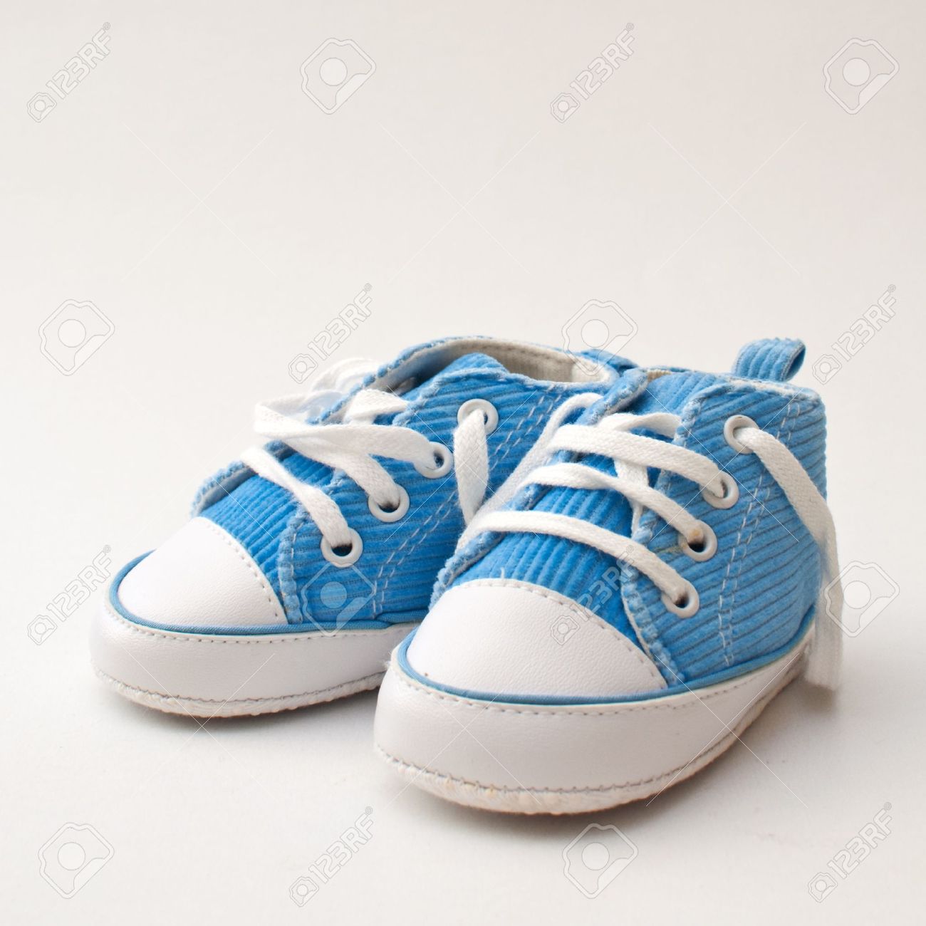 pair of blue and white baby sneakers over a light gray background stock LSZVJFM