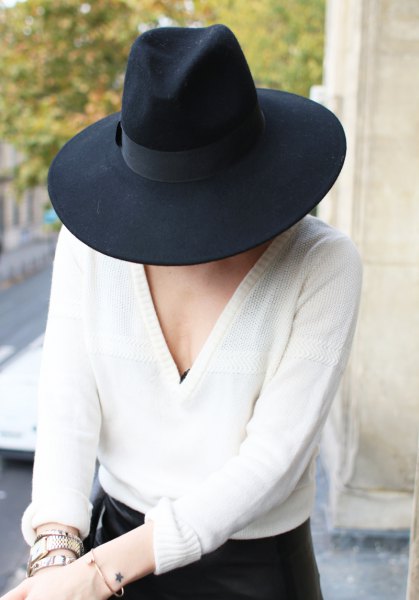 Black fedora with white V-neck sweater and skinny jeans