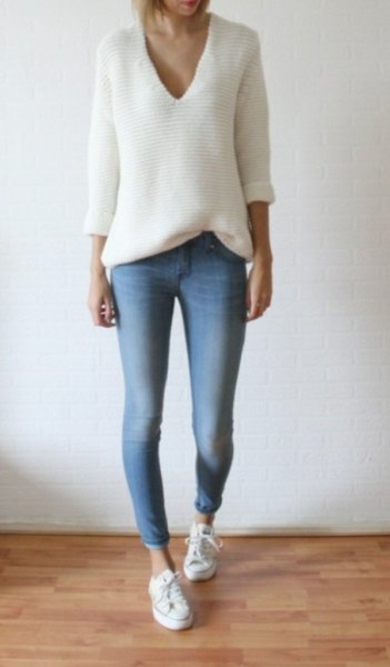 White loose fitting V-neck knit sweater paired with light blue skinny jeans