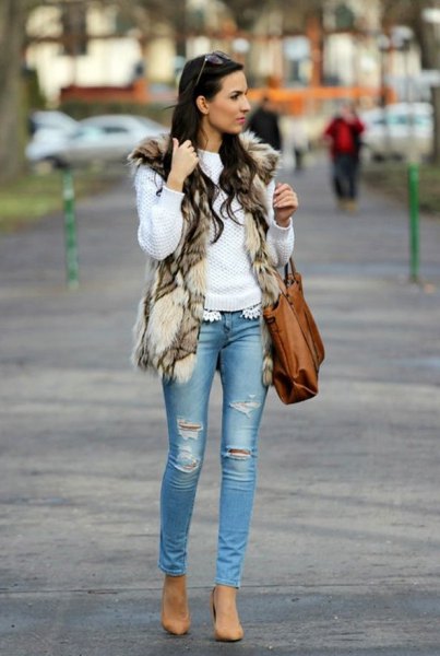 White sweater with faux fur vest and light blue ripped skinny jeans