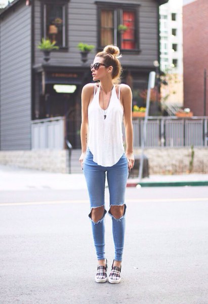 White relaxed fit scoop neck tank top paired with blue ripped skinny jeans