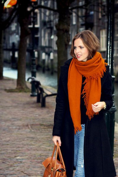 black long wool coat with blue skinny jeans and orange knitted scarf