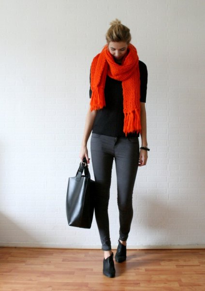 black sweater with orange fringed scarf and gray skinny jeans
