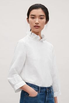 White blouse with a stand-up collar and blue skinny jeans