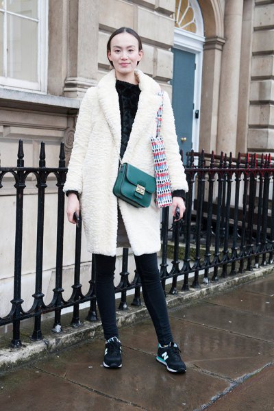 White fleece coat with black leather handbag slung over shoulder