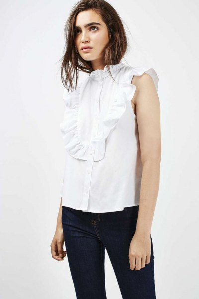 White sleeveless shirt with ruffles at front and black skinny jeans
