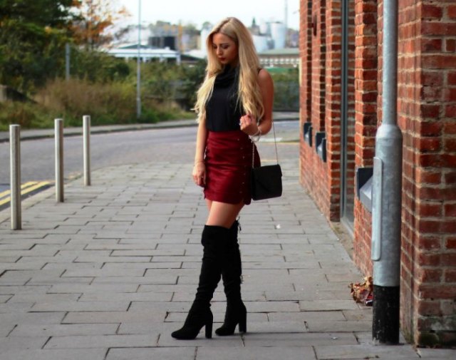 Black sleeveless high neck top with burgundy mini skirt and tall heeled boots