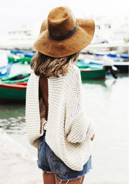White long sleeve oversized sweater with blue jean shorts and floppy hat