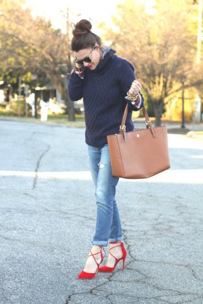 Black cable knit sweater with blue cuffed jeans and red heels