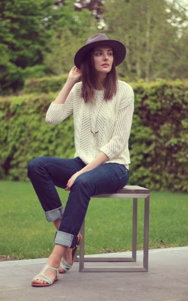 Light yellow knit sweater with dark blue cuffed slim fit jeans and white sandals
