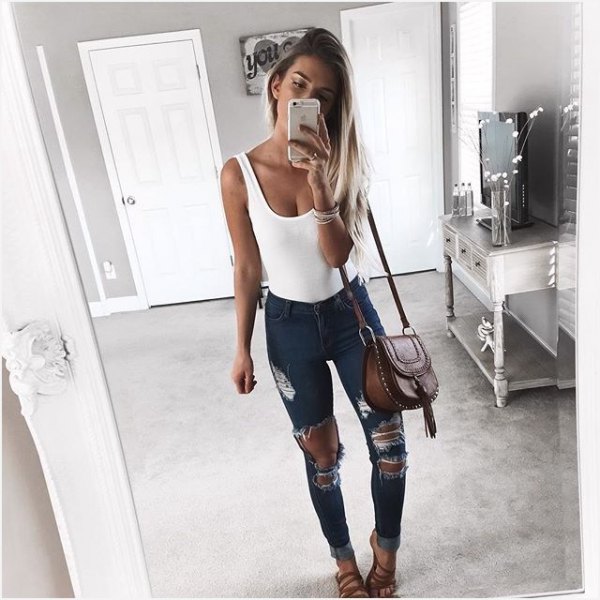 White scoop neck tank top and heavily ripped dark gray skinny jeans