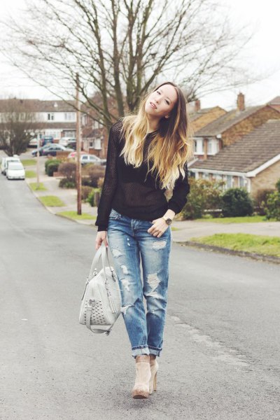 Black semi-sheer sweater worn with ripped jeans and gray heeled
ankle boots