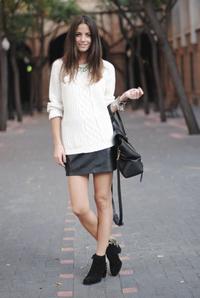 White cable knit sweater with black leather skirt and heeled mini boots