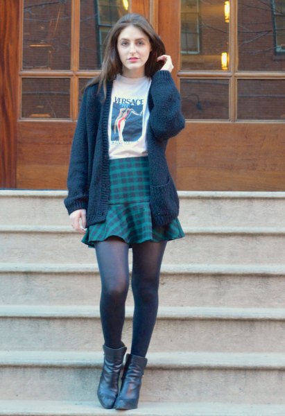 Black knit sweater with white printed t-shirt and navy blue plaid skirt
