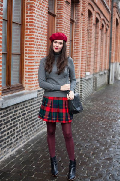 Gray turtleneck sweater with a red and blue checked pleated mini
skirt