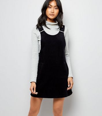 Light gray stand-up collar sweater with black suspender dress