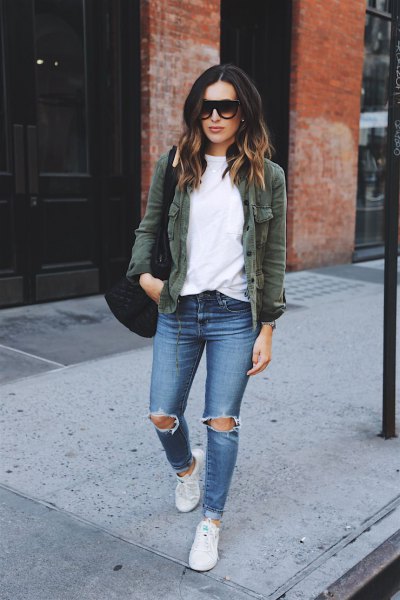 olive green jacket with white sweatshirt and ripped blue jeans