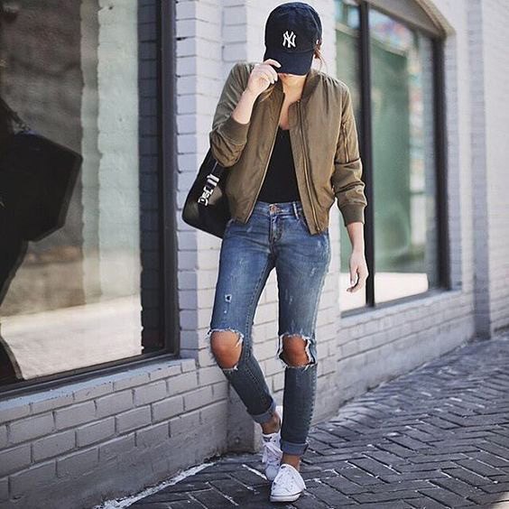 Green bomber jacket with black scoop neck top and badly ripped jeans