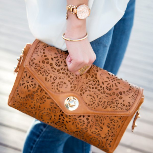 Brown soft leather clutch with cutouts, white chiffon blouse and blue jeans