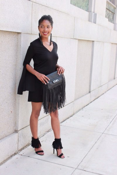 Black mini shift dress with bell sleeves and fringed leather bag