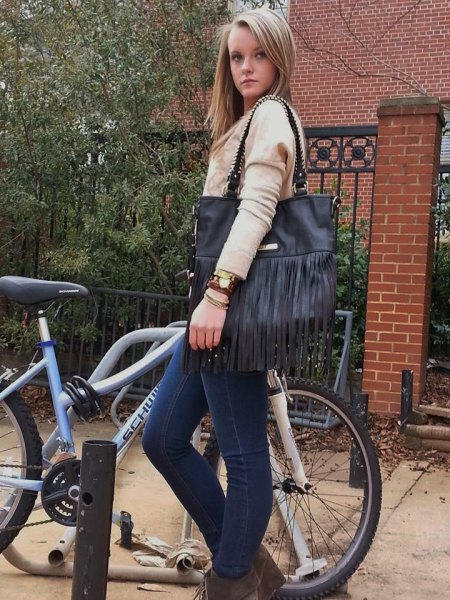 Blush knit sweater with blue skinny fit jeans and black fringed
leather bag