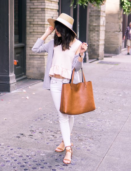 Straw hat with a cashmere cardigan draped over the shoulder and a crop top