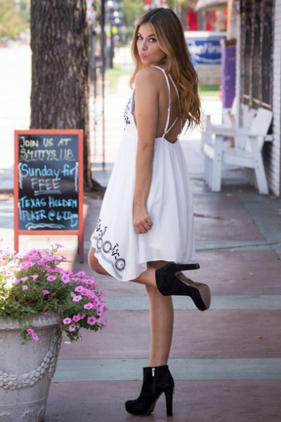 White midi babydoll dress with an open back and black suede ankle boots