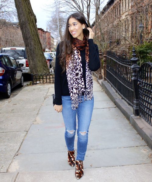 Black sweater with a leopard print scarf and light blue jeans