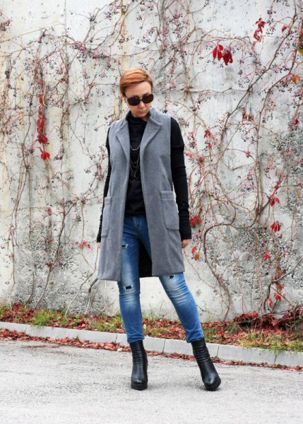 long gray wool vest with blue drainpipe jeans and black sweater