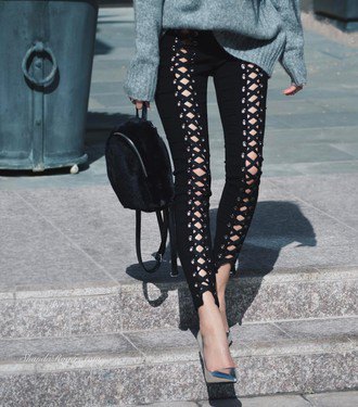 gray coarse knit sweater with black leather trousers with lace-up neckline and cutouts