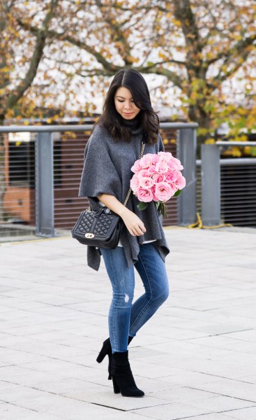 gray poncho sweater with half sleeves, blue jeans and black boots