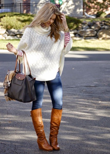 White cable knit poncho sweater with blue skinny jeans and brown leather knee high boots