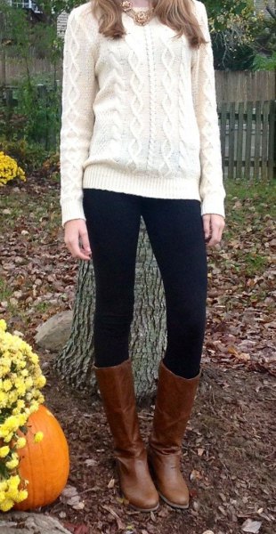 White cable knit sweater with black leggings and brown knee high leather boots