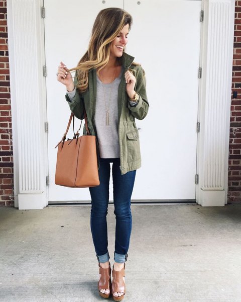 olive green jacket with gray sweatshirt and dark blue skinny jeans with cuffs