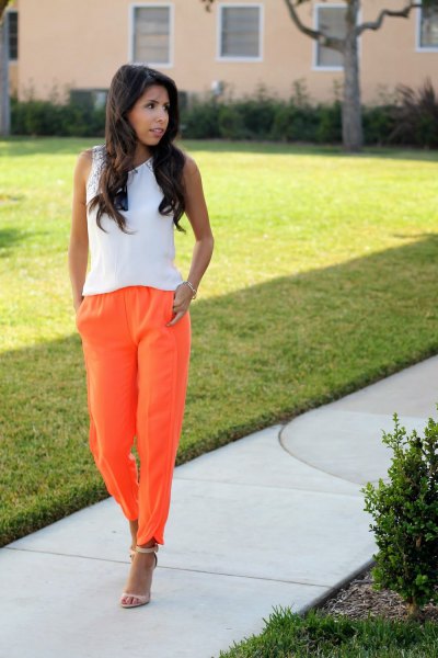 white sleeveless top with orange pull-on jeans