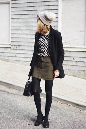 Black and white patterned sweater with green mini skirt with tie waist