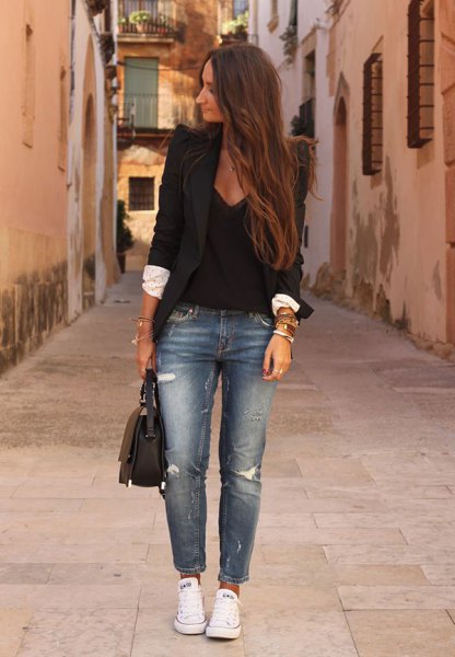 Black blazer with deep V-neck blouse and blue ripped jeans