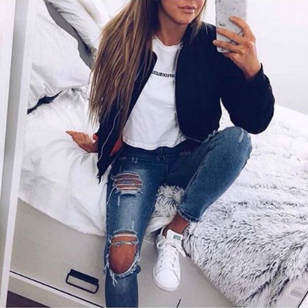 Black bomber jacket with white graphic tee and really ripped blue jeans