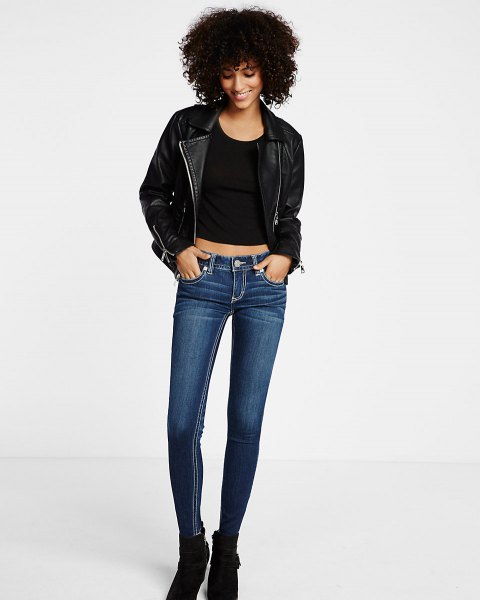 Black leather jacket with a scoop neck crop top and dark blue skinny jeans