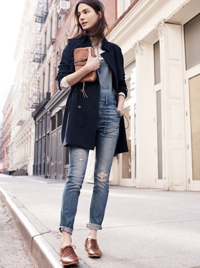 black long wool coat with grey-blue ripped cuffed jeans and brown shoes
