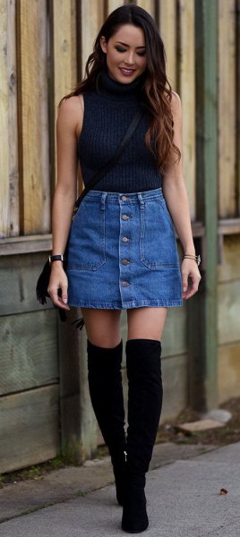 Black sleeveless turtleneck sweater and blue denim mini skirt with front button closure