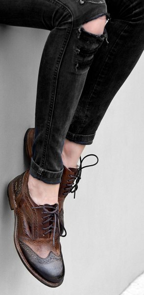 Black ripped skinny jeans and brown wingtip leather shoes