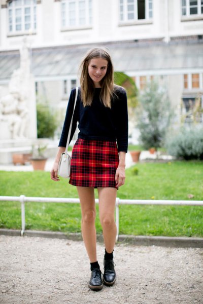 Black sweater with three-quarter sleeves and red plaid mini skirt