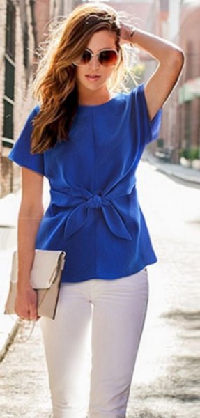 Blue short-sleeved silk blouse with a tie waist and white skinny jeans
