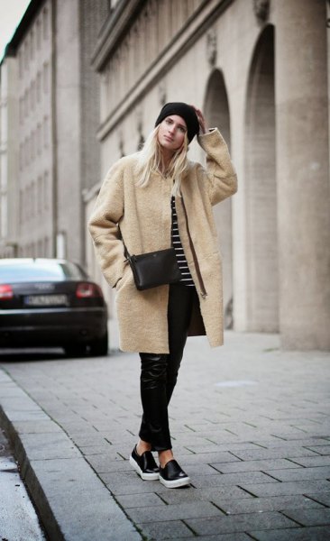 Pale pink long wool coat with black leather pants and slip-on canvas shoes