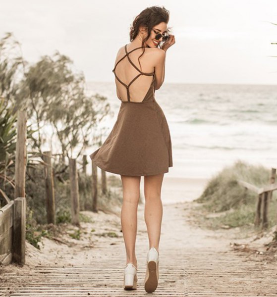 Brown bodycon mini dress with an open back and white platform
heels