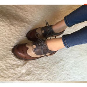 Brown wingtip shoes with dark ankle-length skinny jeans