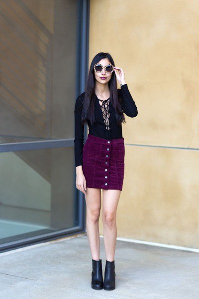 Figure-hugging, low-cut blouse with a black corduroy mini skirt with a button placket at the front