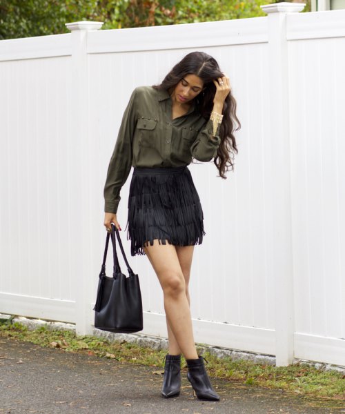 Green shirt with front buttons, black fringed mini skirt and boots