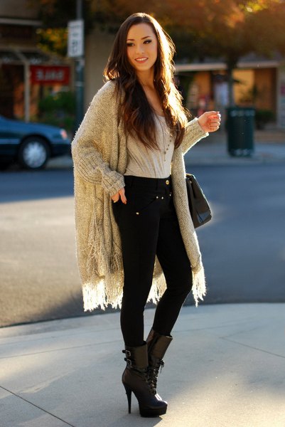 Gray ribbed long sweater with fringes, black skinny jeans and mid-heeled boots